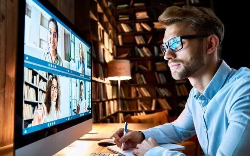homem fazendo anotações enquanto participa de reunião online