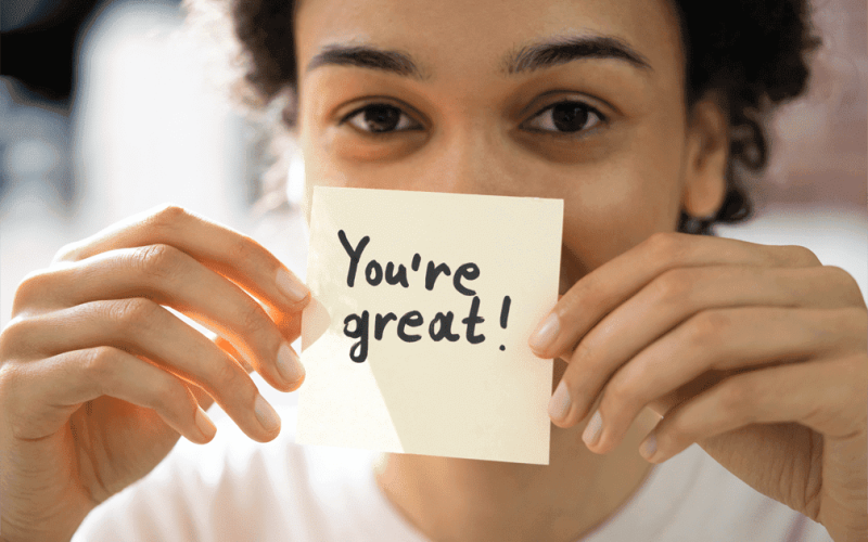 mulher segurando folha de papel escrito "you're great!"