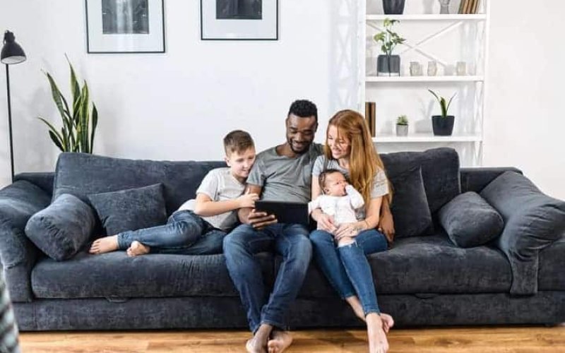 família sentada no sofá assistindo vídeo no tablet